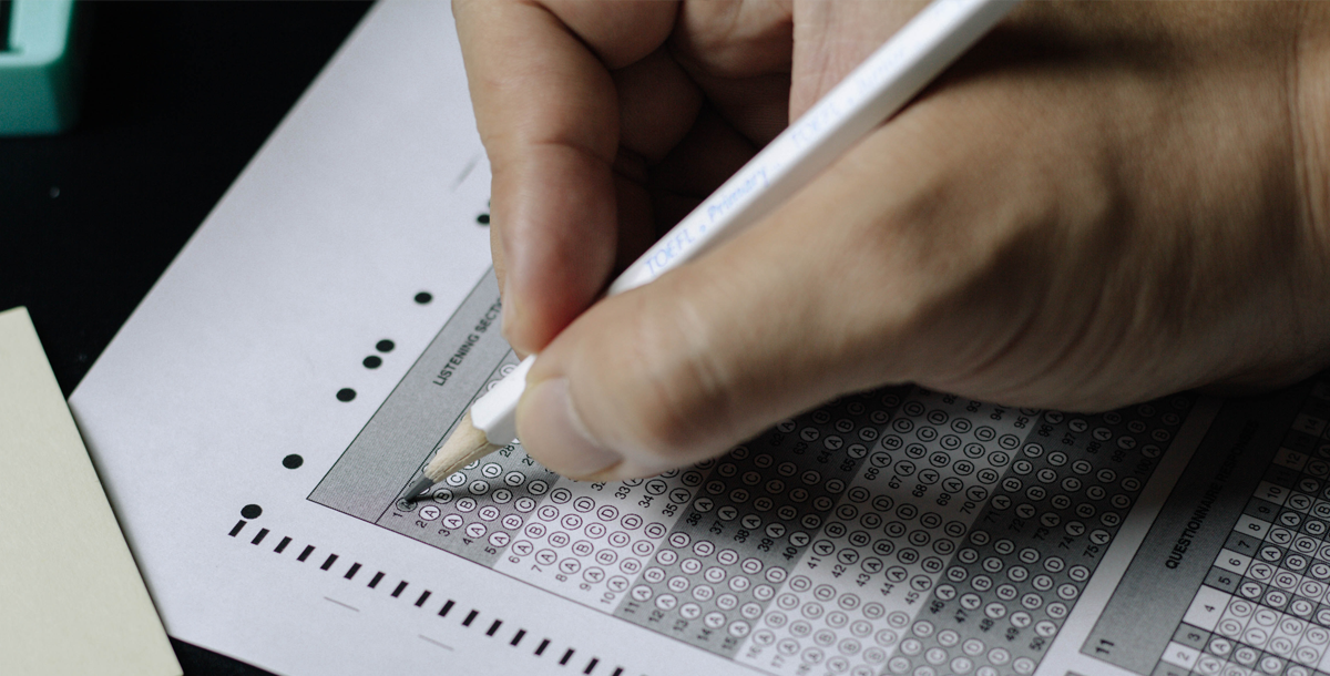 Close-up of a student filling out answer bubbles on a multiple choice exam using a pencil.