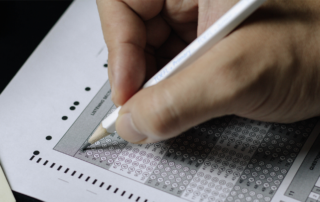 Close-up of a student filling out answer bubbles on a multiple choice exam using a pencil.